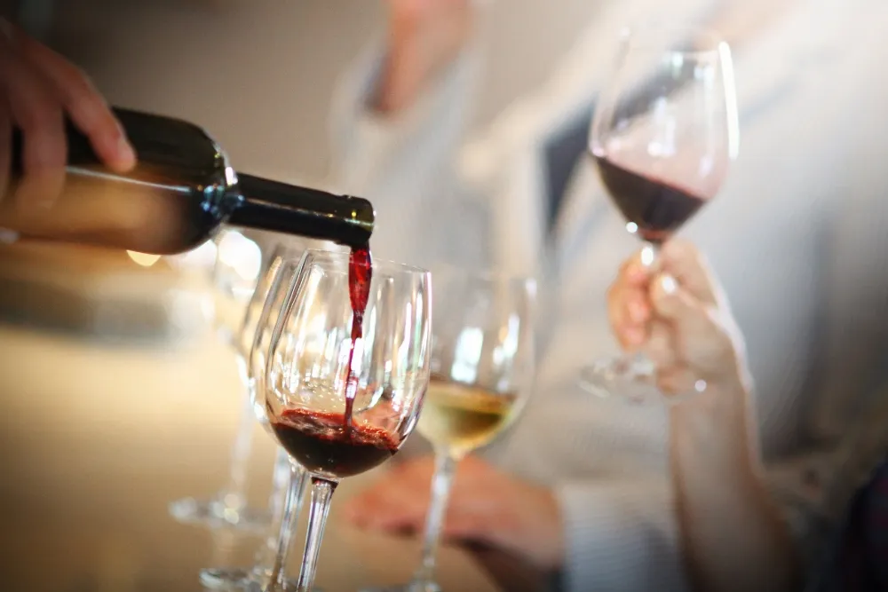 A hand pouring red wine in a glass