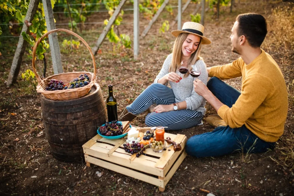 Couple tossing glass of wine with grapes on the side