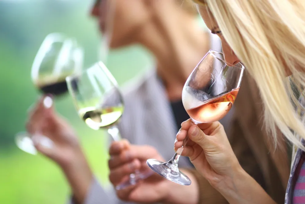 a woman smelling the wine before drinking it