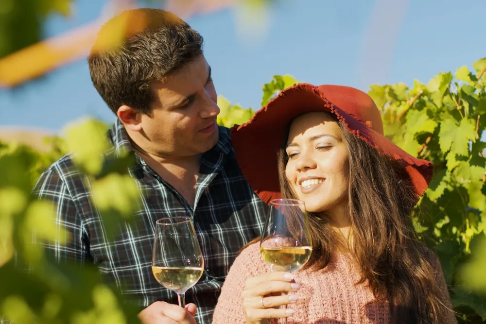 Happy couple having a glass of white wine in the vineyard