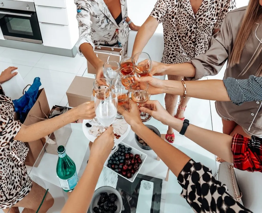 Group of eight women toasting and celebrating their holidays together